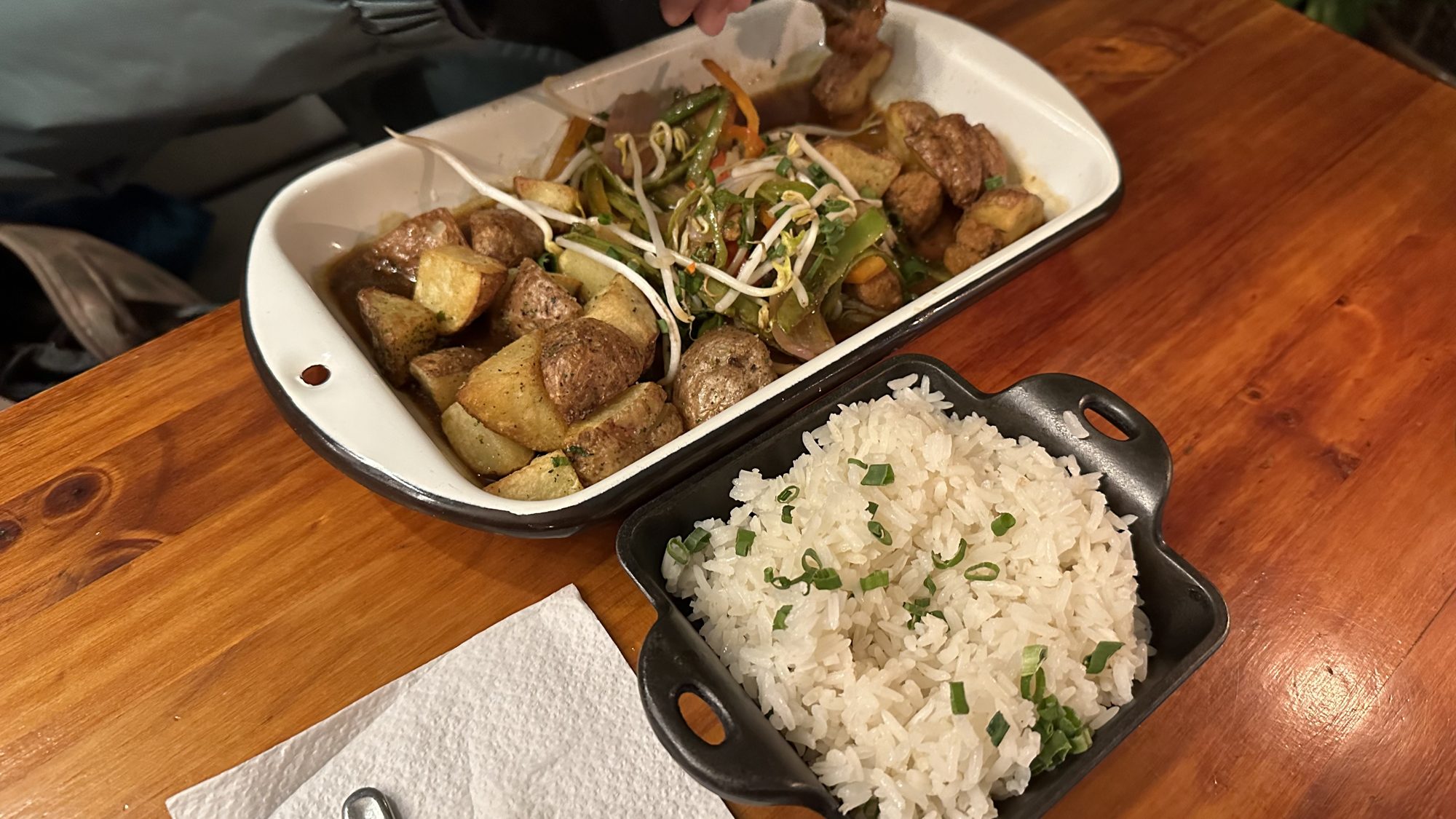 A dish of vegan lomo saltado with a side of rice