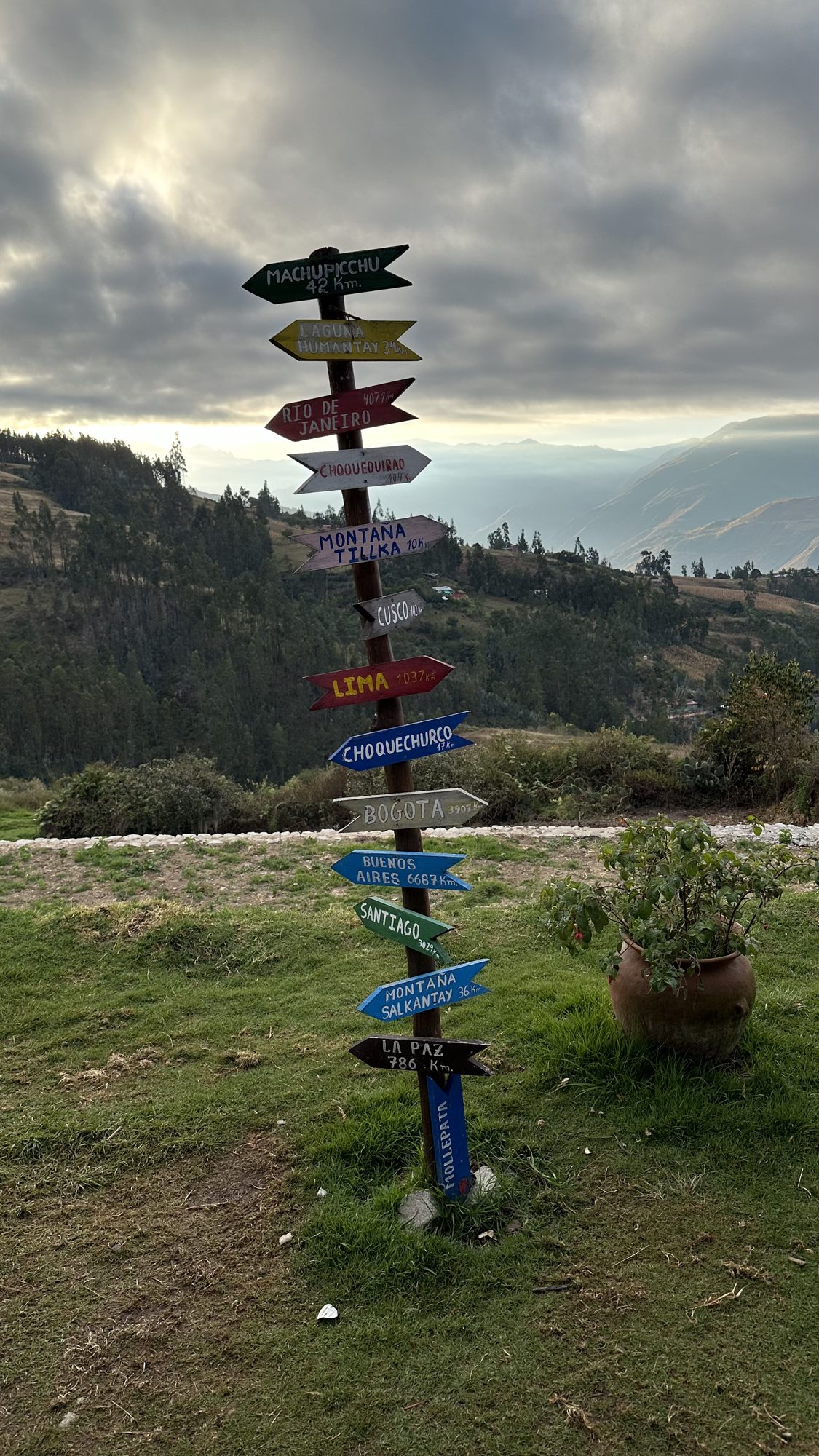A colorful signpost on the grass outside the breakfast restaurant, with hills beyond