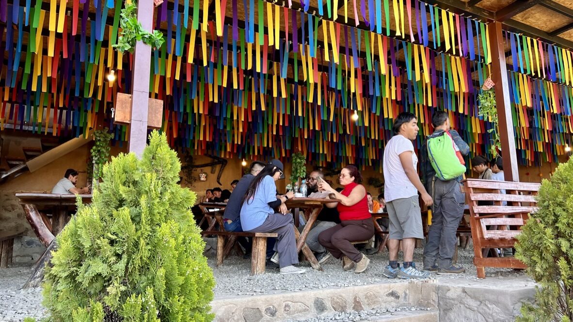 Diners at long tables under a ceiling of colorful painted strips