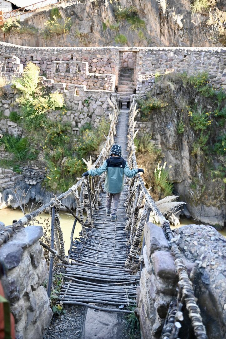 A woven Inca rope bridge spanning a gorge between stone walls