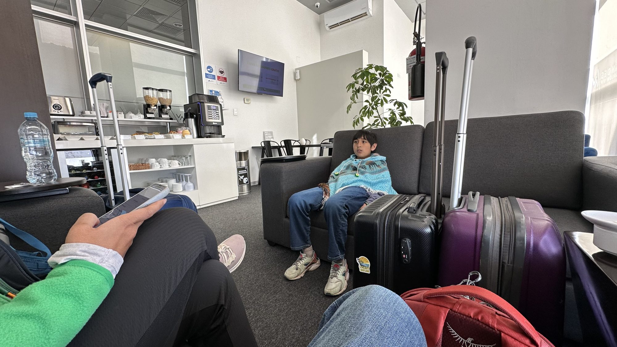 Boy relaxing on a sofa in a small airport lounge, with suitcases nearby
