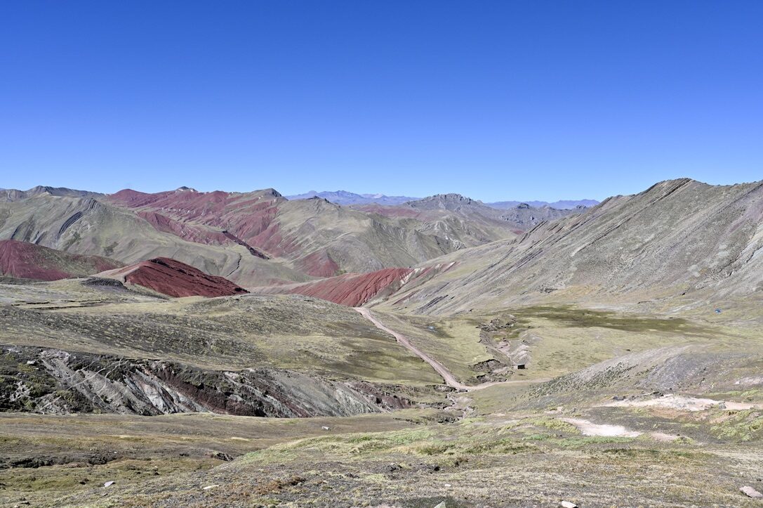 Rainbow-striped mountains in red, green and purple under a blue sky
