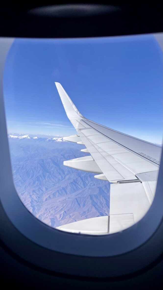 The Andes seen through an airplane window, with the wing in view
