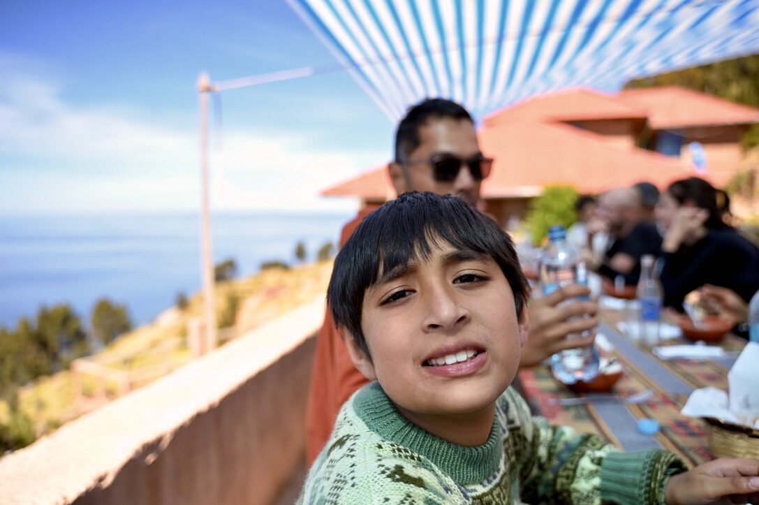 Boy smiling at the lunch table on a sunny deck by the lake
