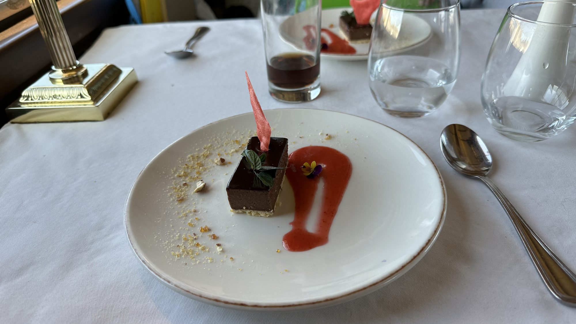 A slice of chocolate cake with red sauce on a white plate