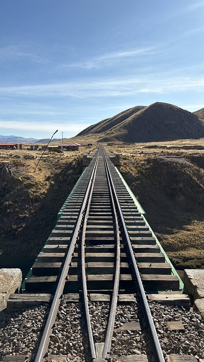 The single track stretching away behind the train across the plain