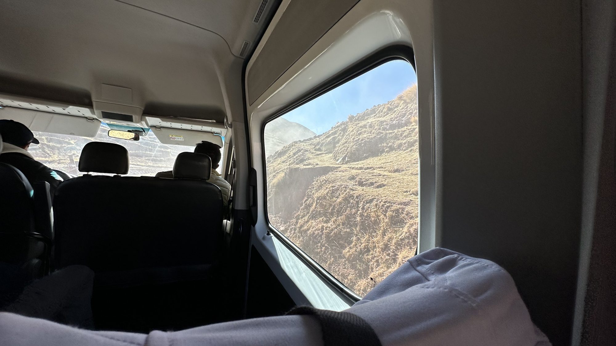The inside of the tour van, looking out the window at dry mountains