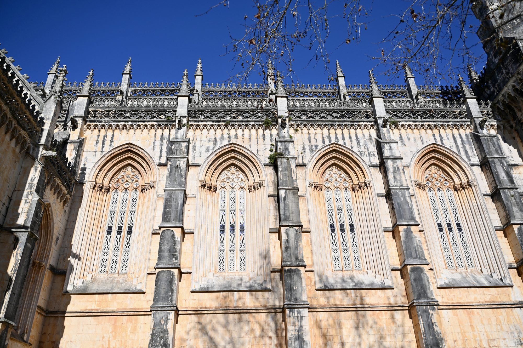 Looking up at the tall, lace-like Gothic windows and pinnacles of the Batalha Monastery.