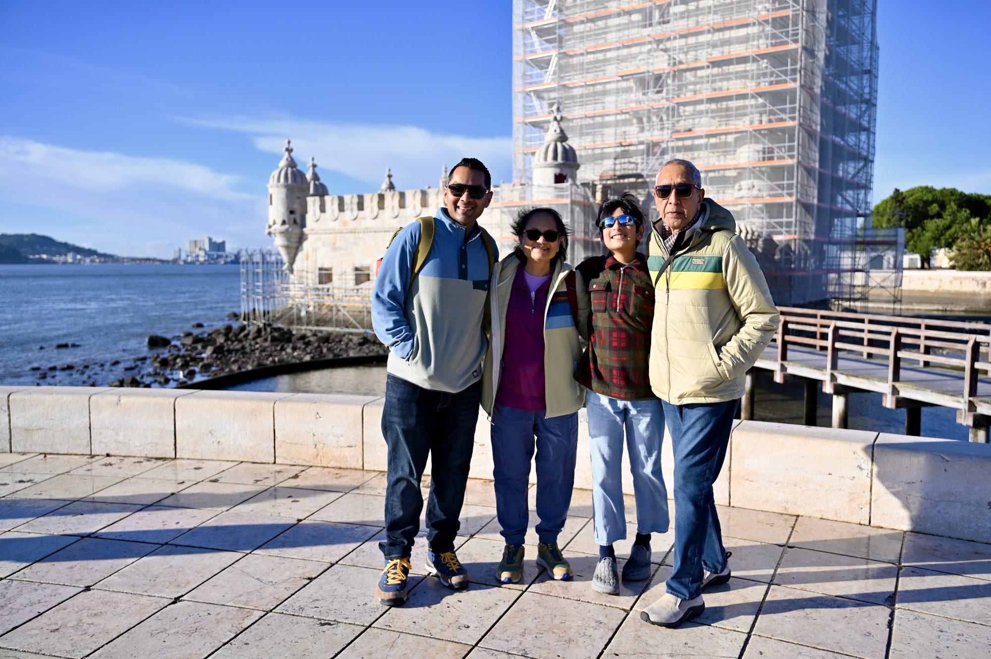 Four of us on the waterfront in front of the Belém Tower, which is partly wrapped in scaffolding.