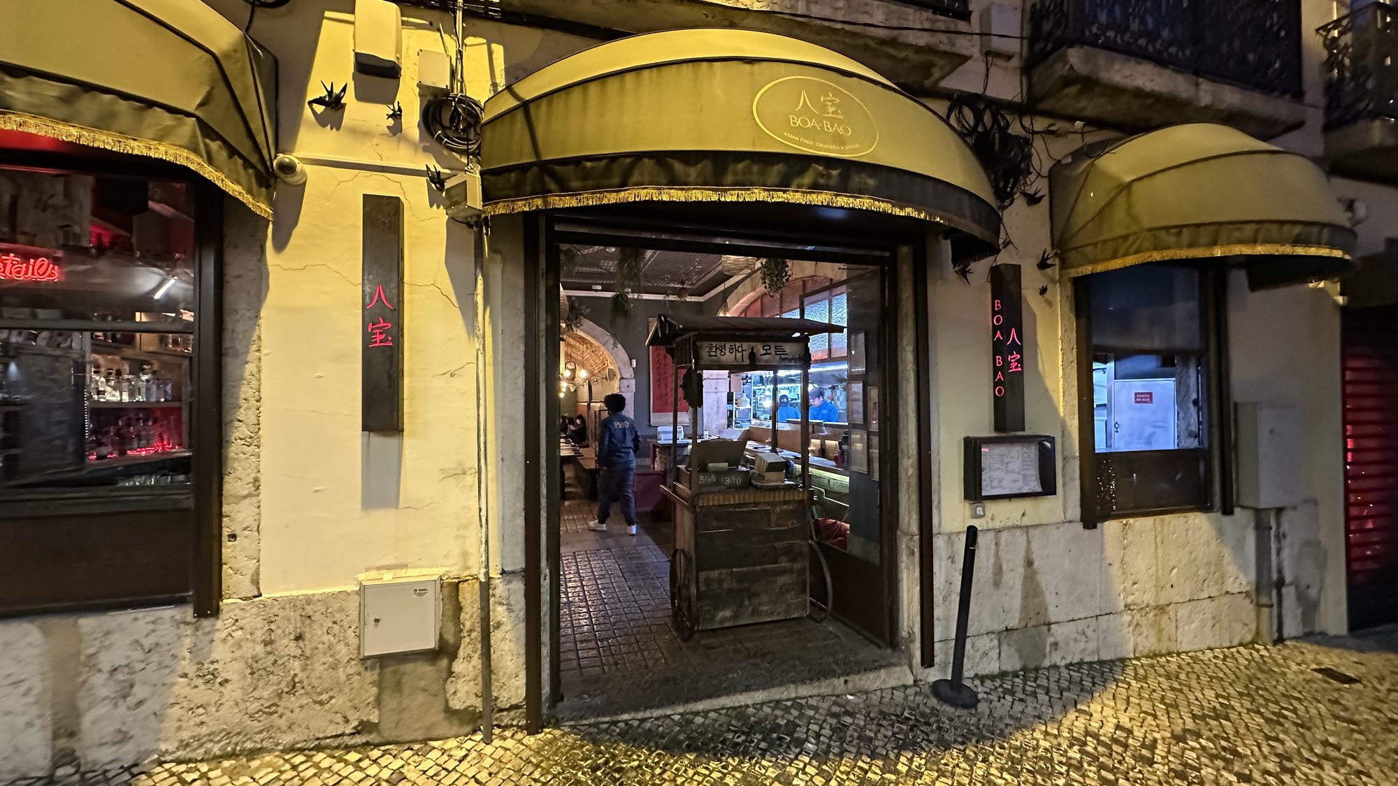 The entrance to Boa-Bao at night, with yellow awnings over the doors.
